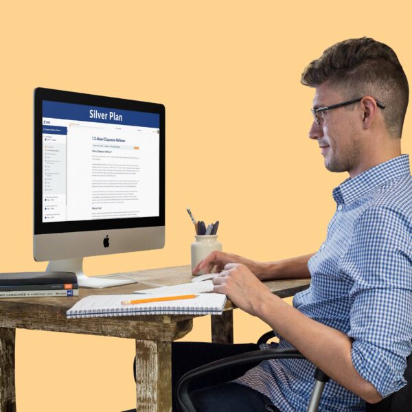 an image showing a man wearing collared shirt with eyeglasses, pencil and notebook on a table looking at an Apple mac desktop computer, searching Chapmans Reflexes Silver plan online flexible self-paced English course